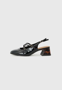 Schwarze Lackleder-Slingback-Schuhe mit überkreuzten Riemen, runder Spitze und einem niedrigen, skulptierten Absatz in braun-schwarzem Muster.