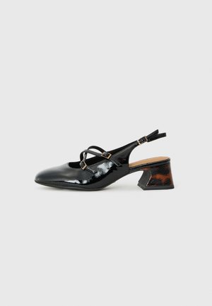 Black patent leather slingback shoes with crossover straps, round toe, and a low, sculpted brown and black patterned heel.