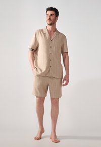 Lys beige kortermet skjorte og shorts sett, laget av lett stoff, med et subtilt stripemønster og tre frontknapper.