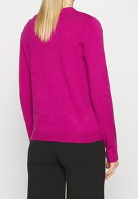 Fuchsia Pullover mit lässigem Schnitt, langen Ärmeln und geripptem Saum. Der Stoff wirkt weich mit einer leicht strukturierten Oberfläche. Rückansicht gezeigt.