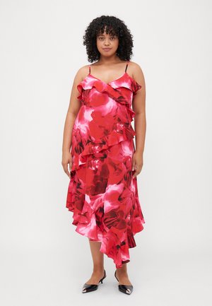 Rød blomstret satin kjole med volanger, spaghetti-stropper, asymmetrisk kant og en glatt, blank overflate. Kombinert med svarte hæler.