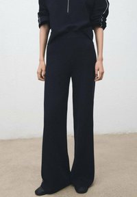 Črne široke hlače iz mehke tkanine, z visokim pasom in sproščenim krojem, s gladko teksturo brez vidnih vzorcev.