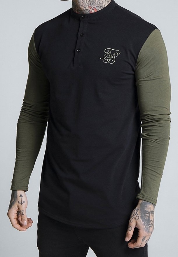 Black long-sleeve henley shirt with olive green sleeves, featuring a crew neck, three black buttons, and a gold logo detail on the chest.