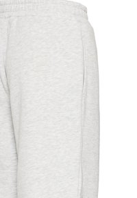 Svetlo šedé tepláky vyrobené z mäkkej zmesi bavlny, s elastickým pásom a postrannými vreckami. Povrch sa zdá byť hladký s jemnými vzormi.