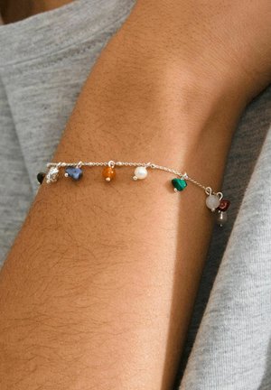 Silberne Kettenarmband mit sieben bunten Edelstein-Anhängern in verschiedenen Formen, darunter rund, tropfenförmig und unregelmäßige Designs.