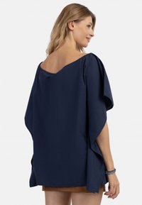 Top blu navy, morbido e leggero, con scollatura ampia e maniche corte e fluide. Texture soffice con design drappeggiato e spacchi laterali.