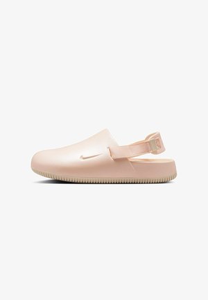 Zuecos Nike en rosa claro, diseñados con un acabado suave y brillante. Presentan una correa trasera acolchada y una suela de goma texturizada para mayor agarre.