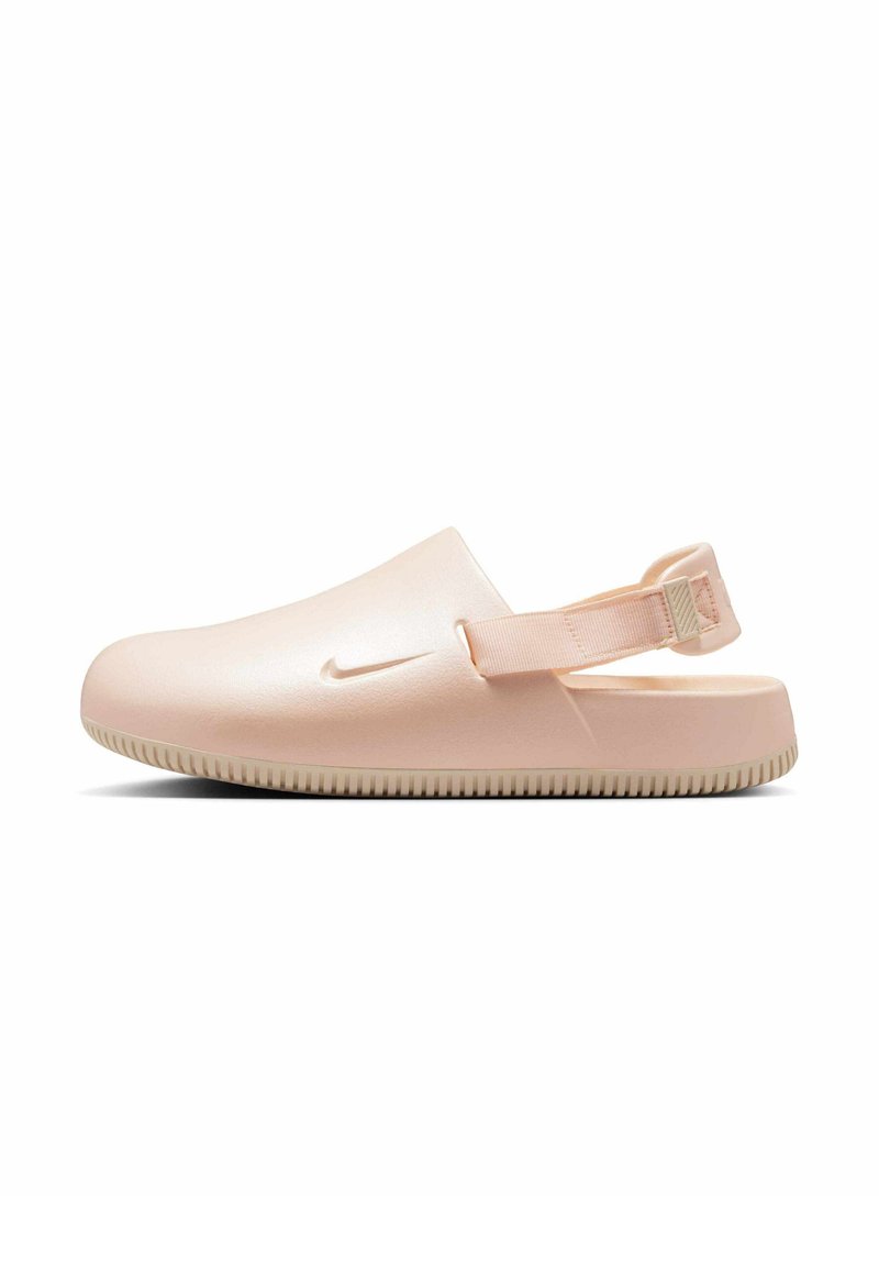Zuecos Nike en rosa claro, diseñados con un acabado suave y brillante. Presentan una correa trasera acolchada y una suela de goma texturizada para mayor agarre.