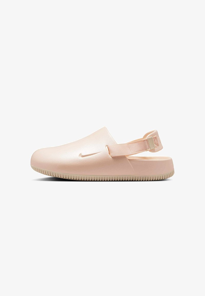 Zuecos Nike en rosa claro, diseñados con un acabado suave y brillante. Presentan una correa trasera acolchada y una suela de goma texturizada para mayor agarre.