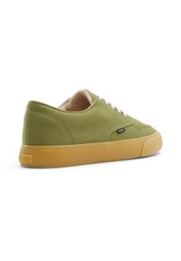 Green canvas sneakers with a low profile, beige interior lining, white laces, and a gum rubber sole. Small logo on the side.
