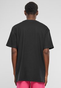 Sort bomulds t-shirt med korte ærmer, rund halsudskæring, afslappet pasform og en glat tekstur, vist fra ryggen med minimale detaljer.