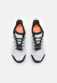 Chaussures de sport blanches et menthe avec des accents noirs. Dotées d'une tige en maille, de perforations pour la respirabilité et de lacets noirs. Semelles intérieures rouges.