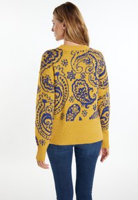 Geel gebreid sweater met een blauw paisleypatroon, geribbelde onderkant en manchetten, met lange mouwen en een losse pasvorm.
