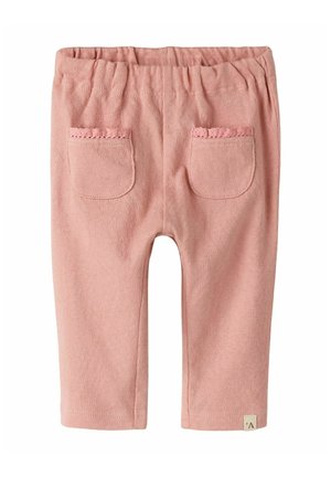Pantalon bébé rose avec taille élastique, deux poches avant bordées de dentelle, et petite étiquette en tissu près de l'ourlet.