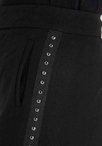 Zwarte rok met een textuurzijdepaneel en glanzende ronde studs. Inclusief een zijzak en een soepele tailleband.