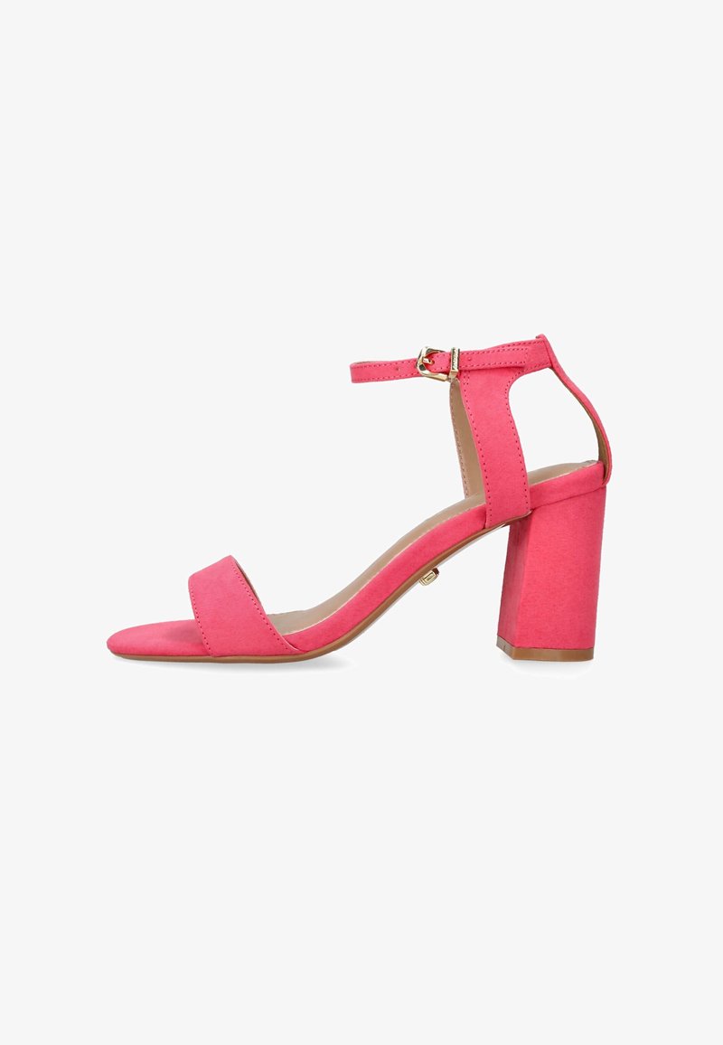 Sandale à talon en daim rose avec un talon bloc, bout ouvert et brides de cheville comportant une boucle en or. Texture lisse et design minimaliste.