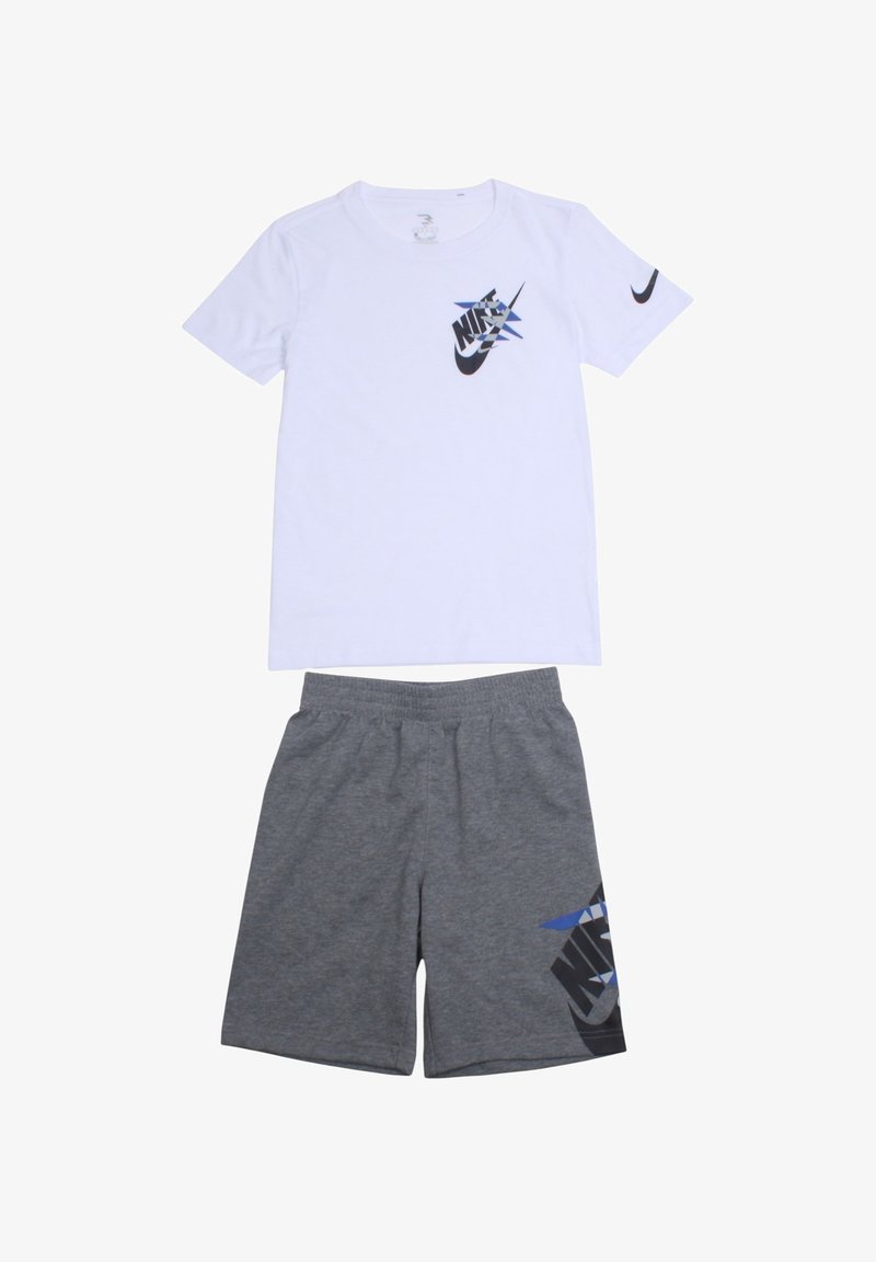 T-shirt blanc à manches courtes avec logo Nike noir et bleu. Short gris avec motif graphique noir et bleu sur le côté. Matière en mélange de coton.
