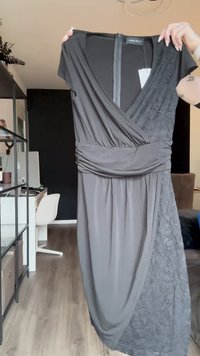 Čierne šaty s prekrývajúcim sa dizajnom, vyrobené z mäkkého materiálu, s textúrovanou čipkou na jednej strane a so zberaným pásom. Zapínanie na zips na chrbte.