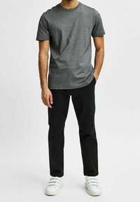 Grå kortärmad t-shirt, rund halsringning, kombinerad med svarta byxor och vita sneakers, med en minimalistisk design och en avslappnad passform.