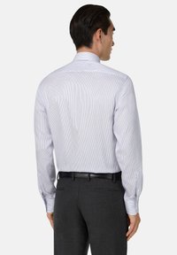 Camisa de hombre de manga larga, azul claro con rayas blancas, mezcla de algodón, cuello clásico, puños abotonados, combinada con pantalones oscuros a medida.