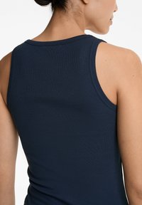 Marineblaues, geripptes Tanktop mit Rundhalsausschnitt und breiten Trägern, das eine strukturierte Oberfläche und eine taillierte Silhouette zeigt.
