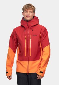 Męska wodoodporna kurtka w czerwono-pomarańczowym kolorze. Posiada kaptur, dwie kieszenie na suwak na piersi, regulowane mankiety oraz oddychający materiał.