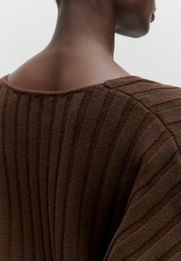 Brown ribbed knit top with a wide neckline, showcasing textured fabric and a fitted silhouette along the shoulder and back areas.