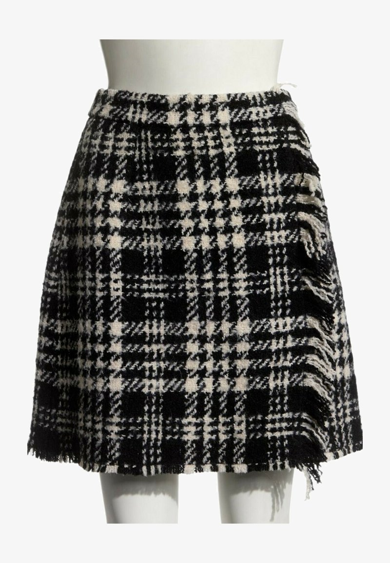 Jupe en laine noire et blanche à motif à carreaux avec des bords frangés, présentée sur un mannequin blanc buste et jambes.