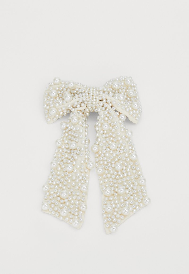 Pärlprydd rosett i off-white tyg med en texturerad yta. Innehåller flera storlekar av runda, glansiga pärlor i olika placeringar.