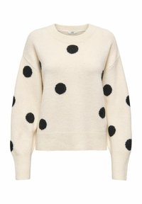 Pull crème avec des pois duveteux noirs, col rond, épaules tombantes, poignets et ourlet côtelés, fabriqué dans une texture douce.