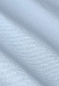 Tissu bleu clair avec une texture lisse, présentant de fines rainures parallèles et un léger éclat. Le matériau semble extensible et doux.