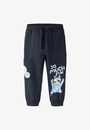 Marineblauwe sweatpants met elastische tailleband en trekkoord. Voorzien van een zijzak en een grafische print van een blauwe hond met de tekst "ZO VEEL PLEZIER."