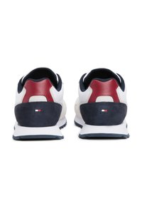 Sneaker bianche e blu navy con accenti rossi, realizzate in una combinazione di pelle e suede, con un tallone prominente e suola testurizzata.