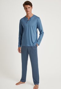 Langarm blauwe henley top met knoopsluiting, gecombineerd met blauwe pyjamabroek met patroon met een geometrisch ontwerp en elastische tailleband.