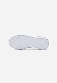 Semelle de sneaker blanche avec des motifs de semelle en grille et des bandes horizontales, présentant un logo Puma près du talon sur un fond blanc uni.