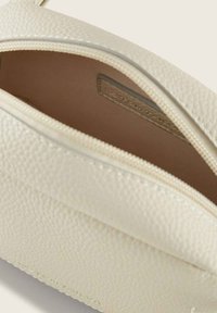 Pochette in pelle bianca strutturata con chiusura a zip, dotata di un interno liscio e di una piccola etichetta all'interno.