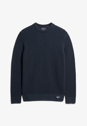 Granatowy sweter dzianinowy z teksturowanym wzorem, okrągłym dekoltem, prążkowanymi mankietami i dołem, z małą naszywką z logo w dolnym prawym rogu.