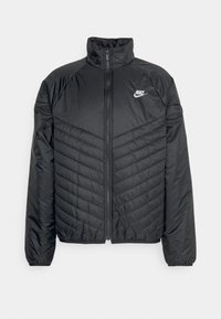 Černá péřová bunda Nike s předním zipem, vysokým límcem a prošívaným diagonálním vzorem na přední straně, se znakem Nike na levé straně.