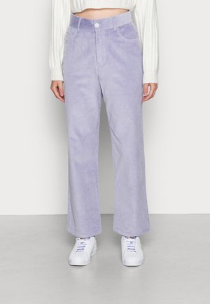 Pantalon large en velours côtelé lavande avec poches avant, porté avec des baskets blanches et un pull court blanc côtelé.