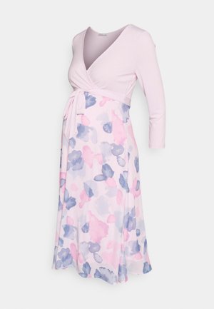 Vestido de maternidade rosa claro com corpete em estilo envolvente, mangas longas e um padrão floral em aquarela nas cores rosa e azul, apresentando um cinto atado na cintura.