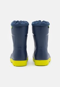 Bottes étanches bleu marine avec un haut en textile froncé et des semelles en caoutchouc jaunes ; caractéristiques d'une finition texturée et de rainures latérales pour une meilleure adhérence.