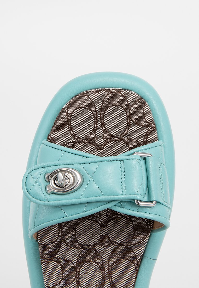 Turkusowe skórzane buty wsuwane z pikowaną paskiem i srebrnymi detalami, z brązowym wzorzystym wnętrzem z przesuniętym wzorem logo.