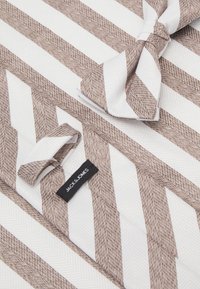 Nœud papillon rayé en blanc et marron clair avec une texture chevrons. Il présente une étiquette en tissu "JACK & JONES" attachée.
