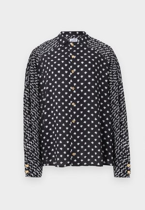 Czarna koszula z długim rękawem z białymi wzorami gwiazd na korpusie i zygzakowatymi liniami na rękawach, z żółtymi guzikami w kształcie kwiatu.