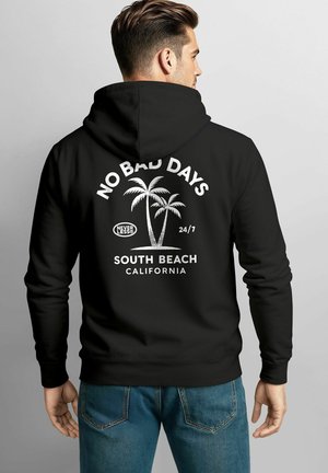 Schwarzer Hoodie mit weißem Text und Palmen-Grafik. Der Text lautet: "KEINE SCHLECHTEN TAGE 24/7 SOUTH BEACH KALIFORNIEN." Weiches Material, lockere Passform.