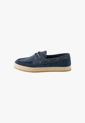 Scarpa da barca da uomo in pelle scamosciata blu navy con suola intrecciata beige e dettagli con lacci sui lati, mostrata di profilo su sfondo bianco.