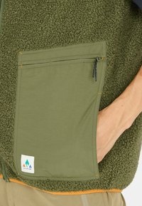 Fleece vest in olijfgroene tinten, met een gestructureerd lichaam en een soepele stoffen zak met een rits, logo-opdruk aan de onderkant.