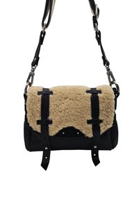 Sac bandoulière avec rabat en shearling beige et sangles en cuir noir, doté de fermoirs en métal et d'une sangle d'épaule réglable.