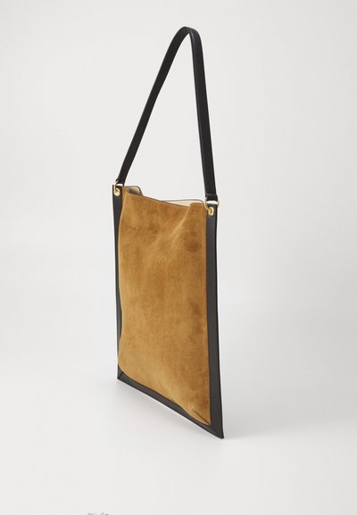 Tote-väska med en mjuk beige mockakropp och kontrasterande svarta läderdetaljer, med en axelrem och guldfärgade metallaccenter.