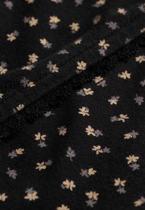 Tela negra con pequeños patrones de tréboles de cuatro hojas en beige y gris y una costura texturizada que atraviesa en diagonal.